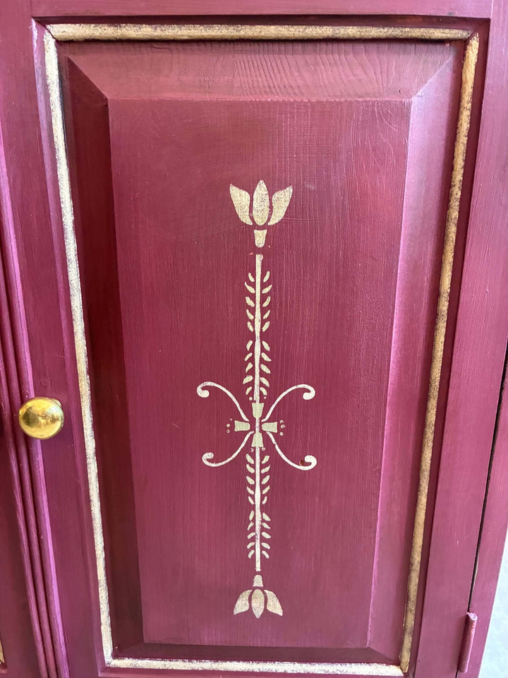 Close-up of aubergine folk art cupboard door featuring gold floral design, crafted by Source for the Goose, Devon.