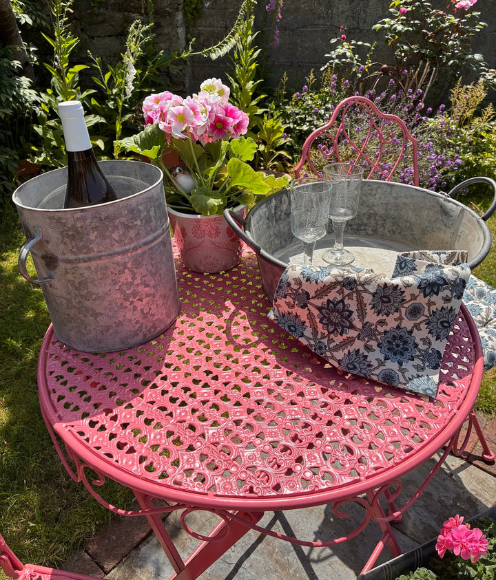 Zinc Round Tray Planter With Handles on pink table with wine, glasses, and flowers in garden.
