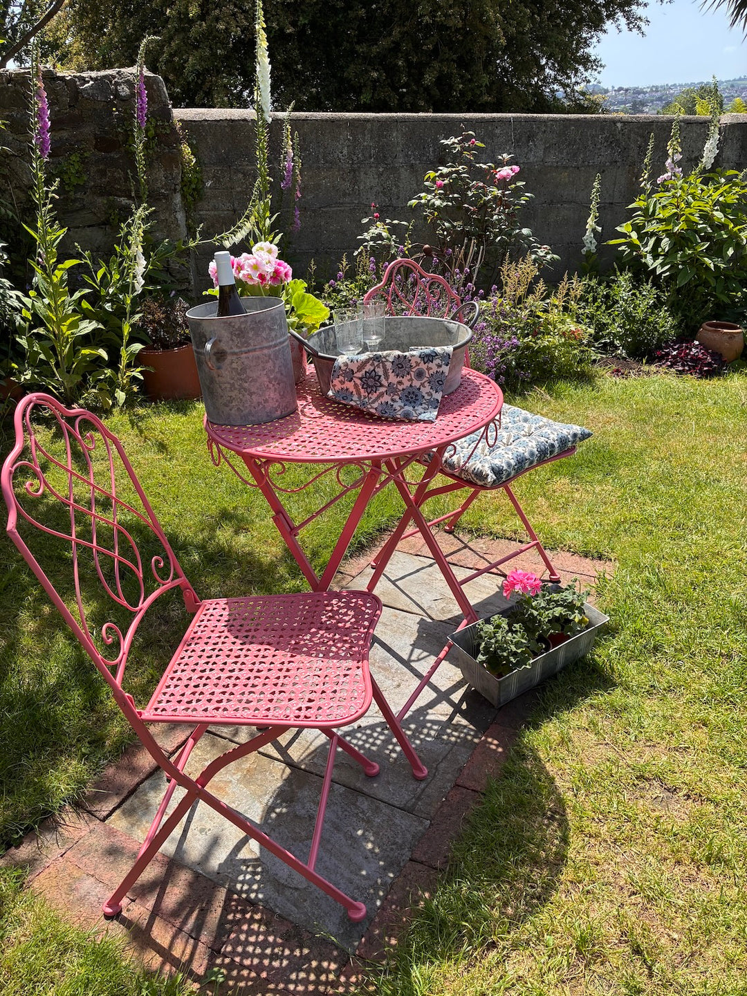 Avalon Rose Pink Garden Bistro Set with floral accents in a sunny garden setting, showcasing vintage charm and delicate design.