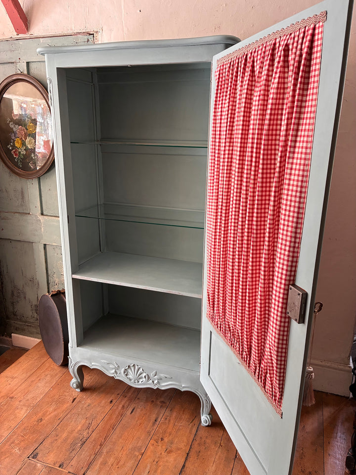 Small Blue Painted French Armoire with half-glazed door and red gingham curtain, ideal for linen storage.