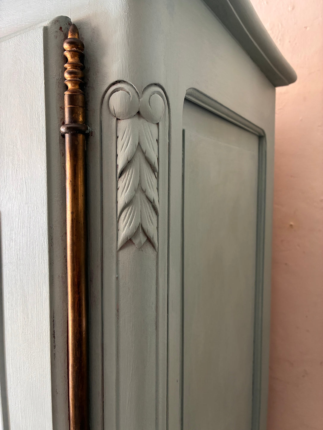 Detail of Small Blue Painted French Armoire showcasing carved leaf design and golden accent handle.