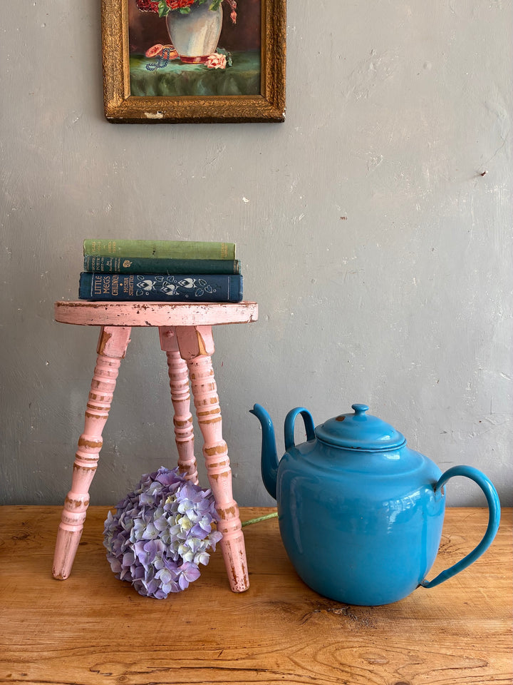Pink Vintage French Milking Stool holding books and flowers beside a blue teapot, perfect for vintage home decor.