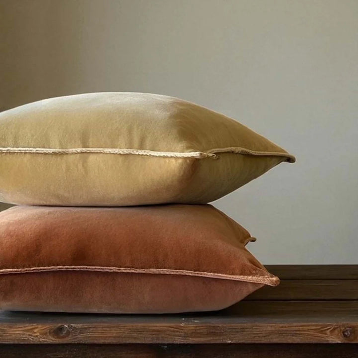 Stonewashed velvet cushions in caramel and dusky pink on a wooden surface, by Source for the Goose, Devon.