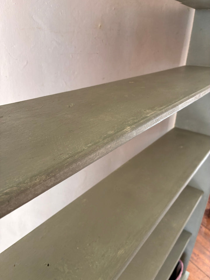 Close-up view of the Tall Chippy Green Bookcase shelves featuring a soft eucalyptus green finish.