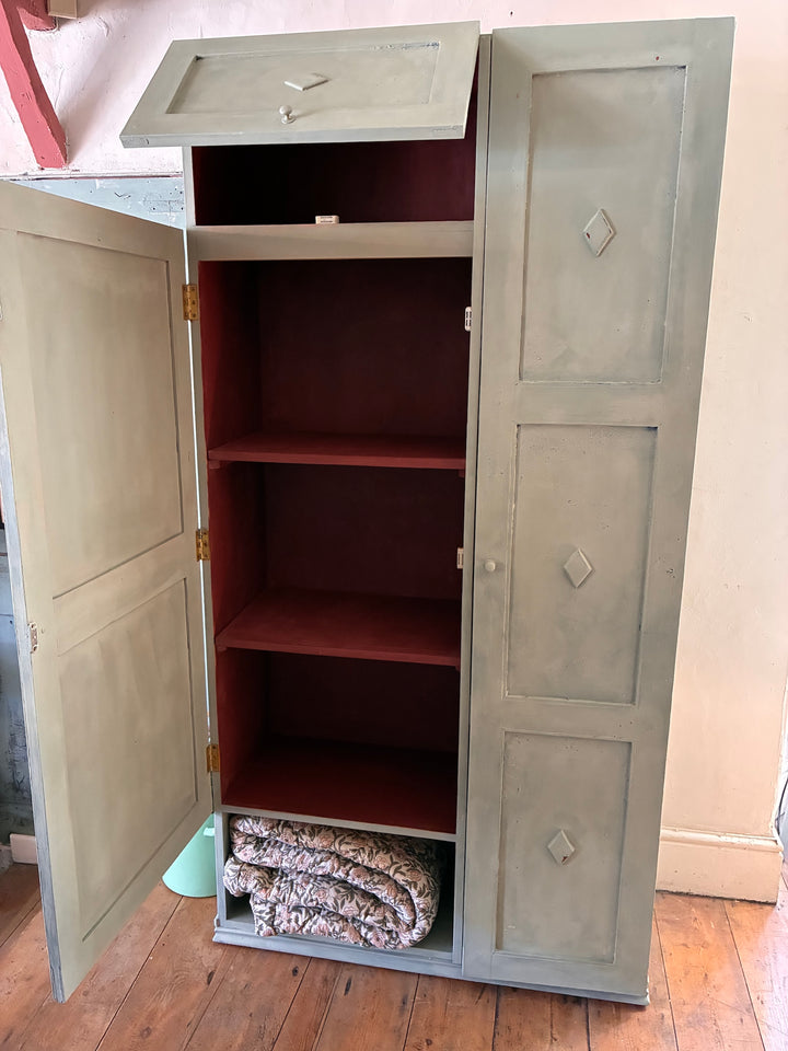 Tall vintage green wooden cupboard with chippy paint and a distressed brick red interior, perfect for stylish storage.