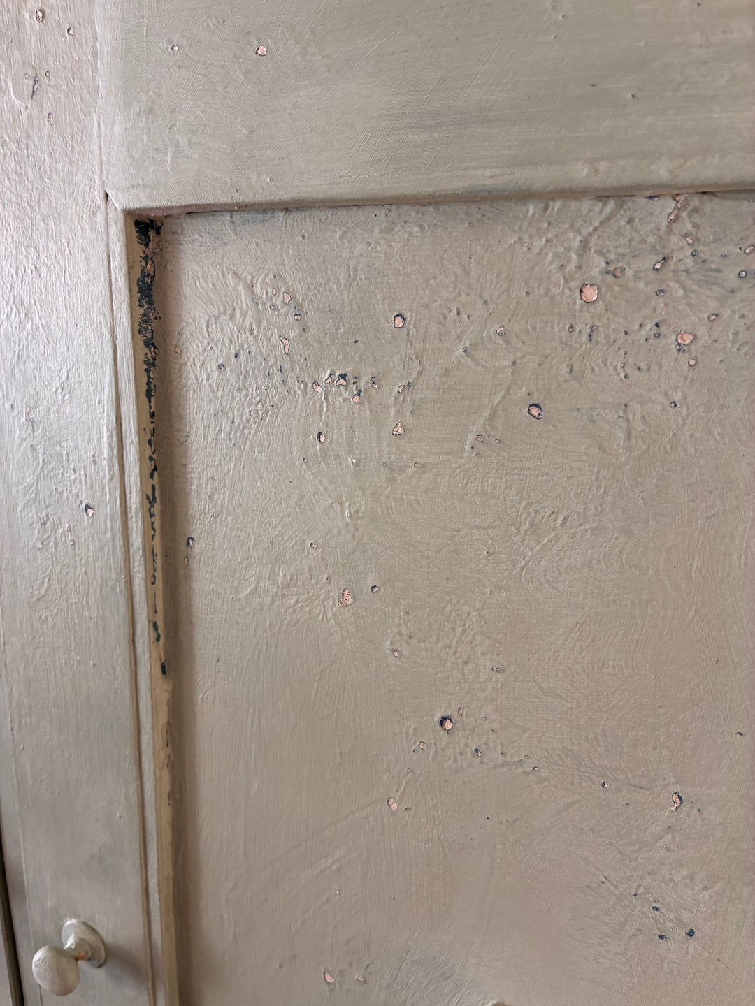 Close-up of weathered paint on a vintage wooden cupboard door, showcasing charming textures and imperfections.