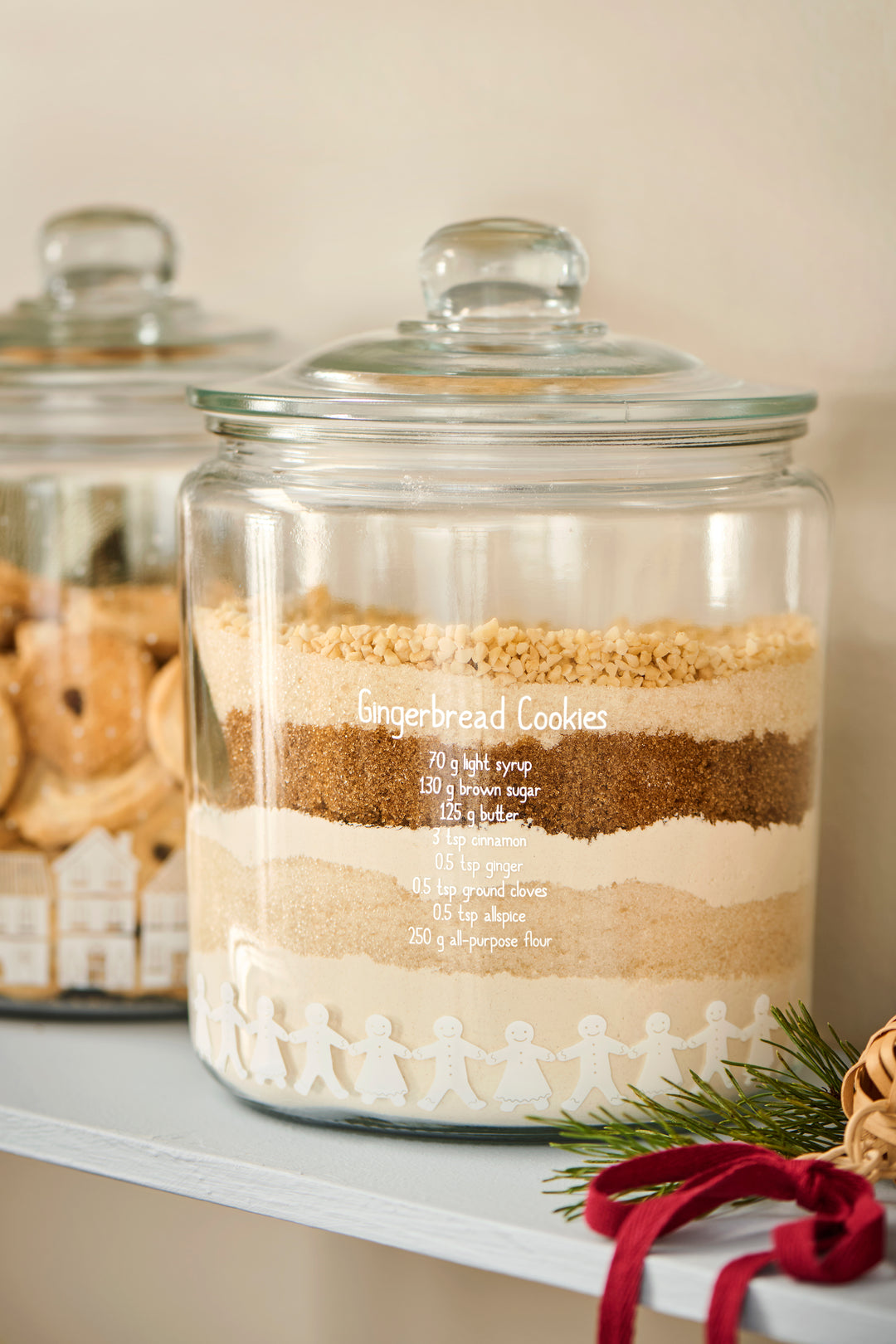 Classical Gingerbread Cookie Glass Storage Jar displaying layered dry ingredients for gingerbread cookies.