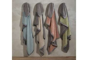 Four soft, colorful throws hanging on a wall, showcasing a mustard yellow cosy sherpa throw.