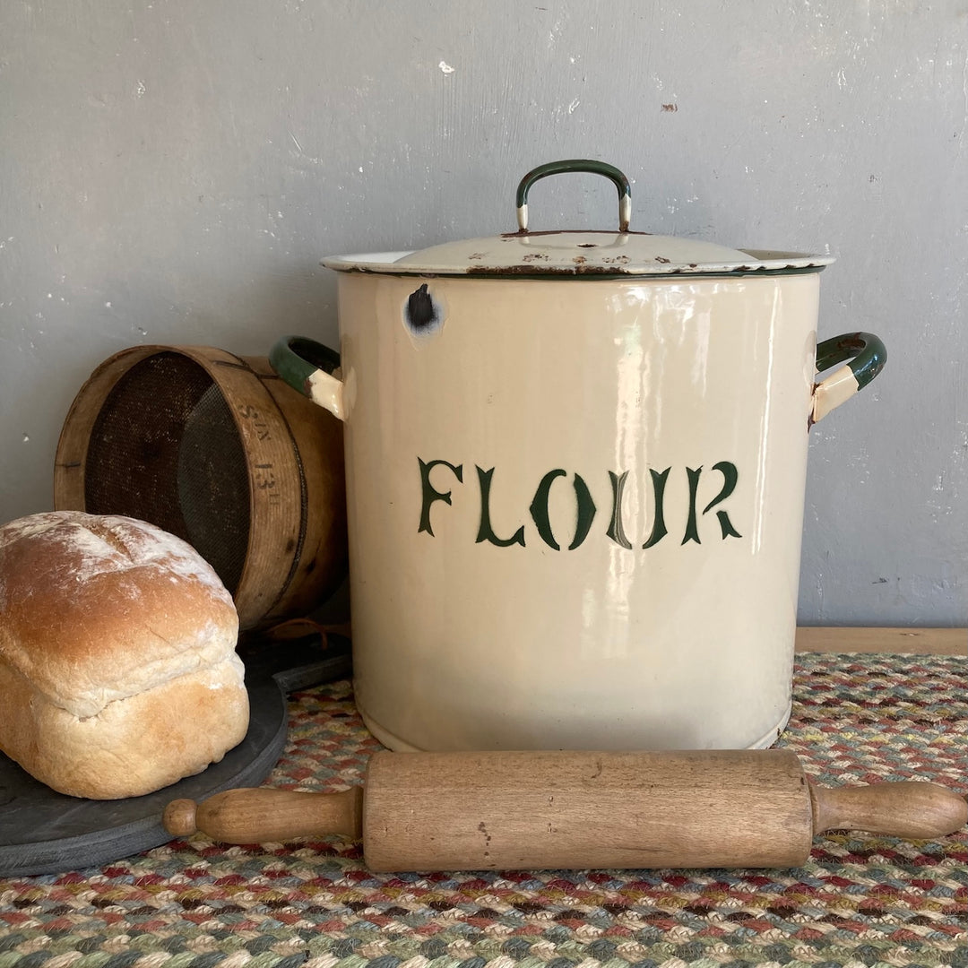 Vintage cream and green flour bin with stylized lettering, wooden rolling pin, and bread, perfect for rustic kitchens.