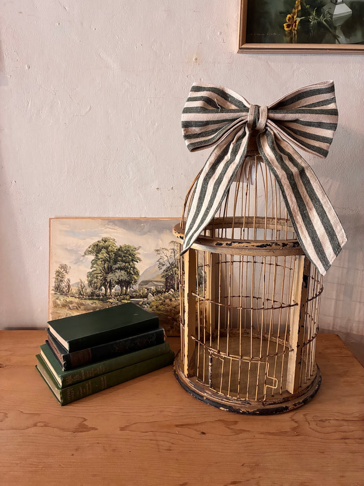 Decorative Antique Wooden Bird Cage with a striped bow and vintage books, enhancing vintage home decor.