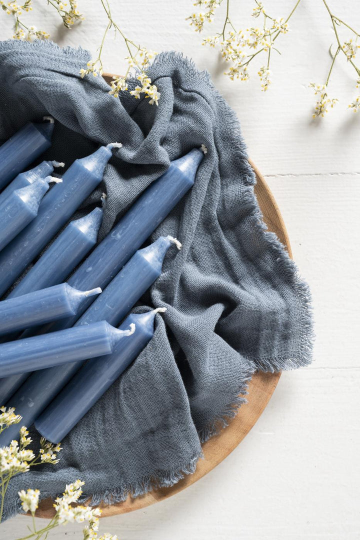 Dusty Blue Stubby Dinner Candle - Bundle of Ten arranged on a grey cloth with floral accents from Source for the Goose Devon.