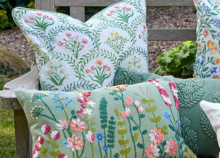 Embroidered Floral Cushion - Keswick featuring hand-embroidered florals and green accents on a garden bench.