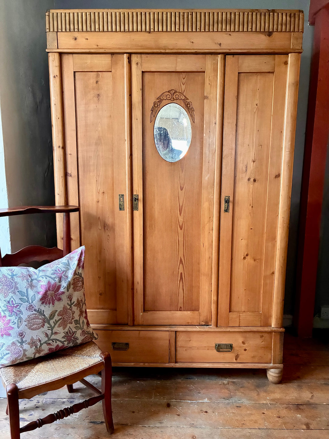 Antique European Pine Wardrobe featuring three panelled doors, oval mirror, and intricate carved detailing.