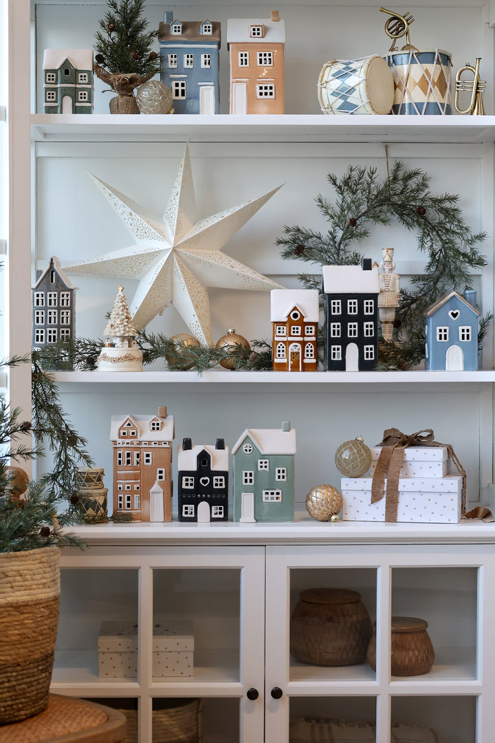 Cozy display of ceramic house tealight holders in assorted colors, creating a festive winter charm in home decor.