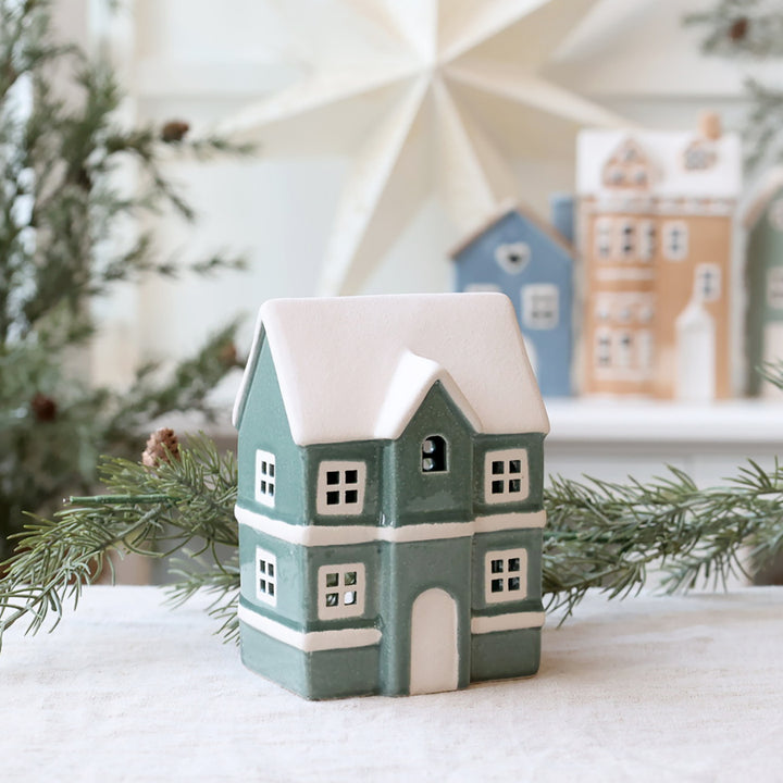 Green ceramic house tealight holder with snowy roof, perfect for cozy winter decor from Source for the Goose, Devon.