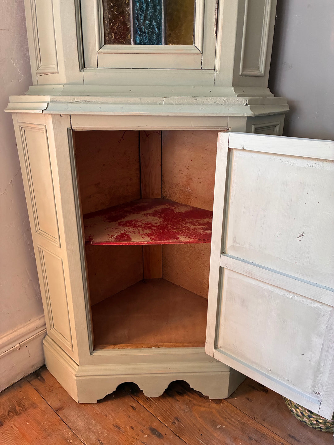 Green Painted Corner Cupboard with Stained Glass Panel showcasing vintage storage and a rustic red shelf.
