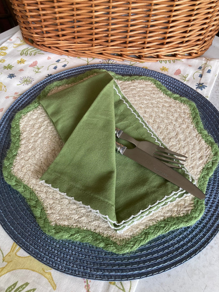 Set of Four Apple Green Scallop Napkins on a woven placemat, perfect for summer dining decor by Source for the Goose, Devon.