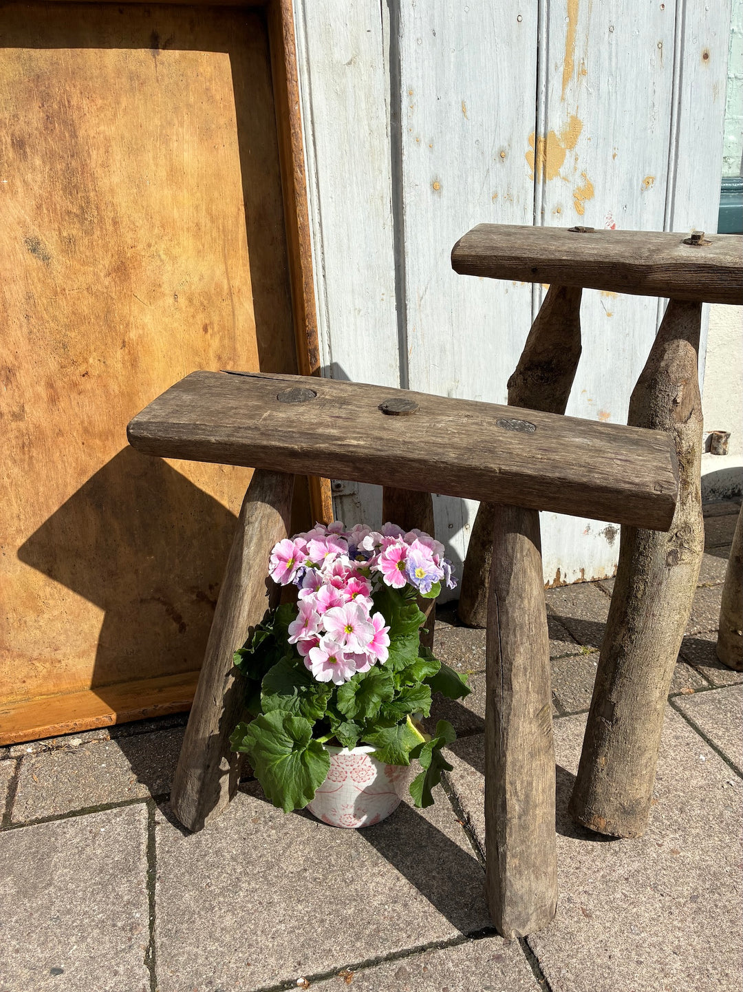 Handmade wooden bodger stool with rustic finish, beside a potted flower, enhancing outdoor charm. Source for the Goose Devon.