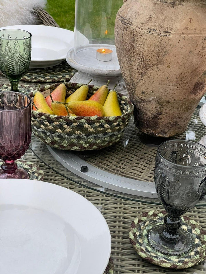 Hedgerow Green Jute Mini Basket filled with pears on a rustic table setting with glassware and an ancient vase.