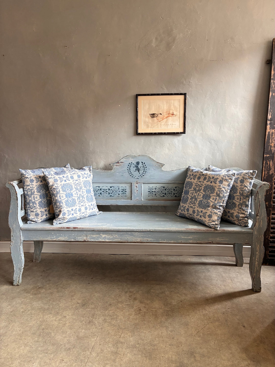 Vintage Long Painted Hungarian Bench with decorative blue cushions against a neutral wall.