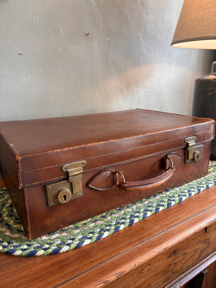 Vintage leather suitcase with initials EHS, brass locks, and vibrant fabric lining, from Source for the Goose, Devon.