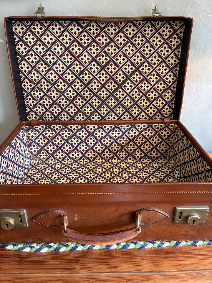 Vintage leather suitcase interior with vibrant patterned fabric lining, sourced from Source for the Goose, Devon.
