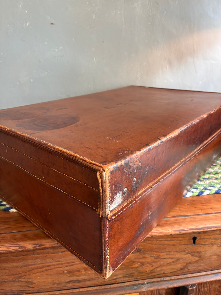 Vintage leather suitcase with initials EHS, featuring sturdy brass locks and rich patina from Source for the Goose, Devon.