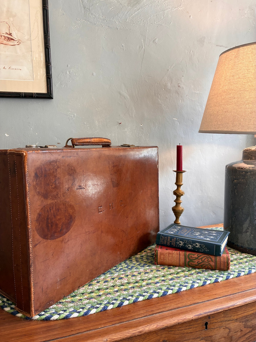 Vintage leather suitcase with initials EHS, styled with books and a candle on a table, from Source for the Goose, Devon.
