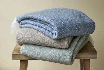 Cozy quilted wool blend throws in blue, taupe, and sage green, perfect for enhancing home comfort. Source for the Goose Devon.