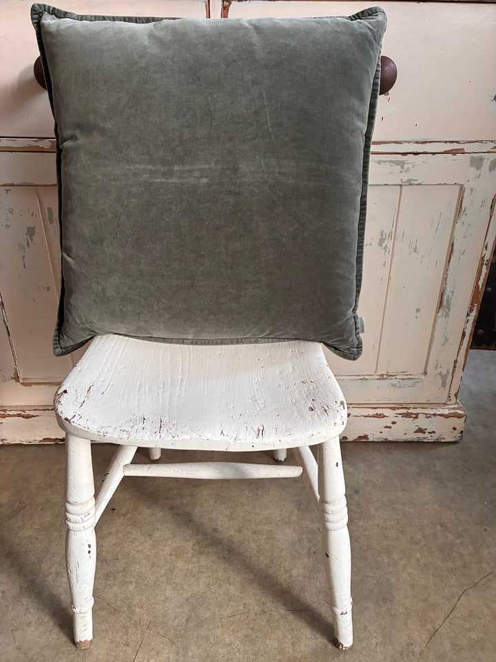 Olive Green cushion on a white distressed chair with a wooden background