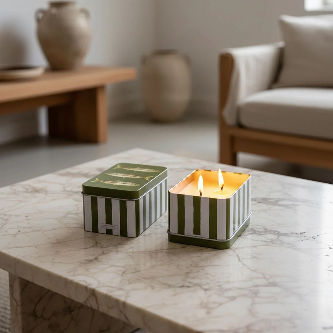 Orange Cordial Scented Candle in a Tin -Green Fish Design displayed on a marble table with two wicks burning.