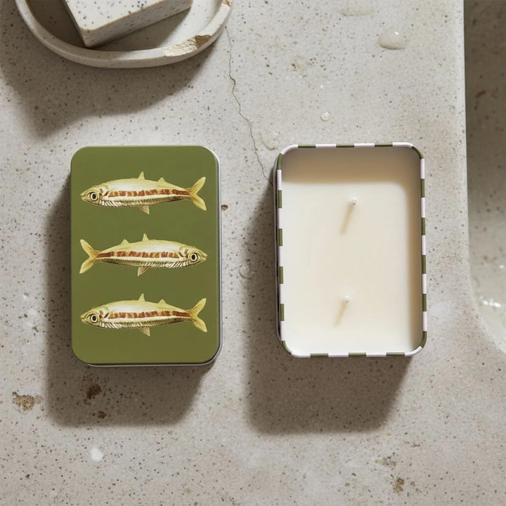 Orange Cordial Scented Candle in a Tin -Green Fish Design displayed on a countertop with a soap dish.