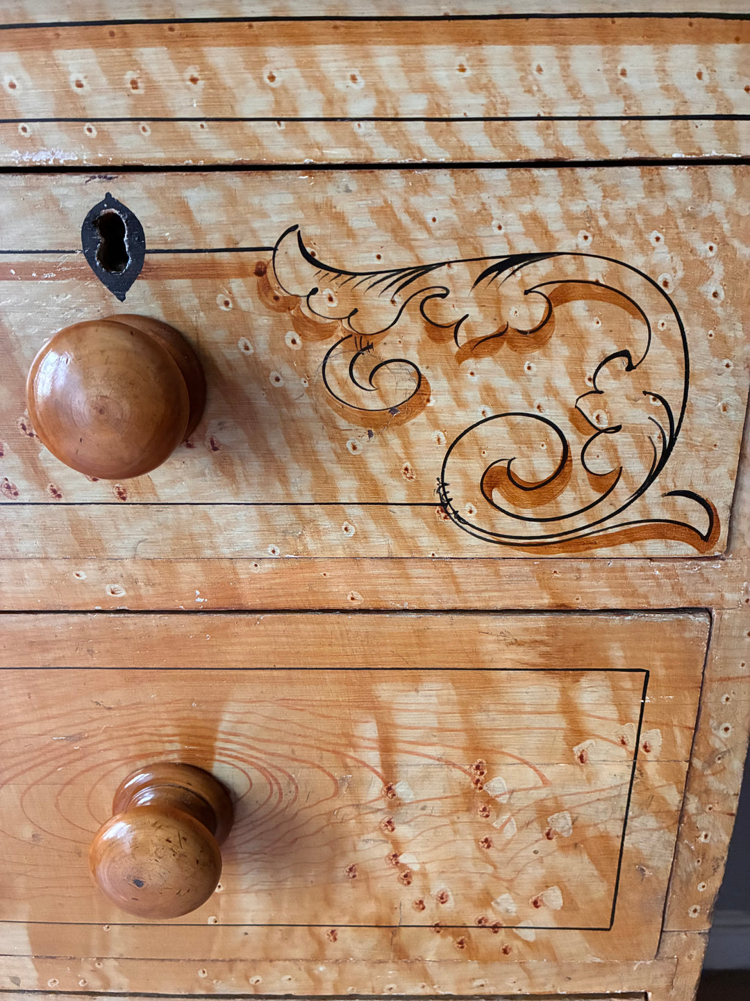 Detailed view of the 19th Century Scumbled Pine Chest of Drawers featuring faux wood grain and decorative accents.