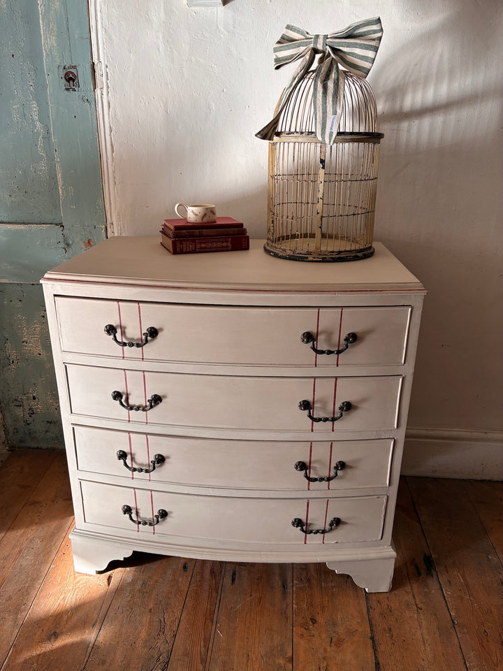 The Georgian Ribbon Chest of Drawers- Hand Painted displayed with books and a birdcage in a vintage home setting in Devon.