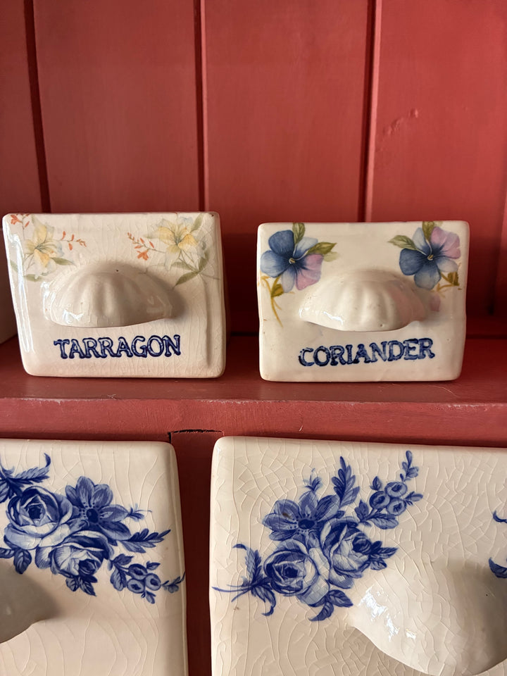 Ceramic drawers labeled Tarragon and Coriander with floral designs, ideal for storing herbs and spices in a kitchen.