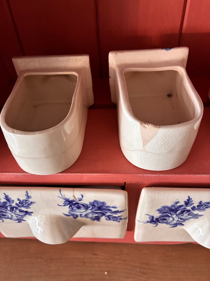 Close-up of ceramic spice drawers in classic blue and cream against a salmon-toned plate rack, showcasing rustic charm.