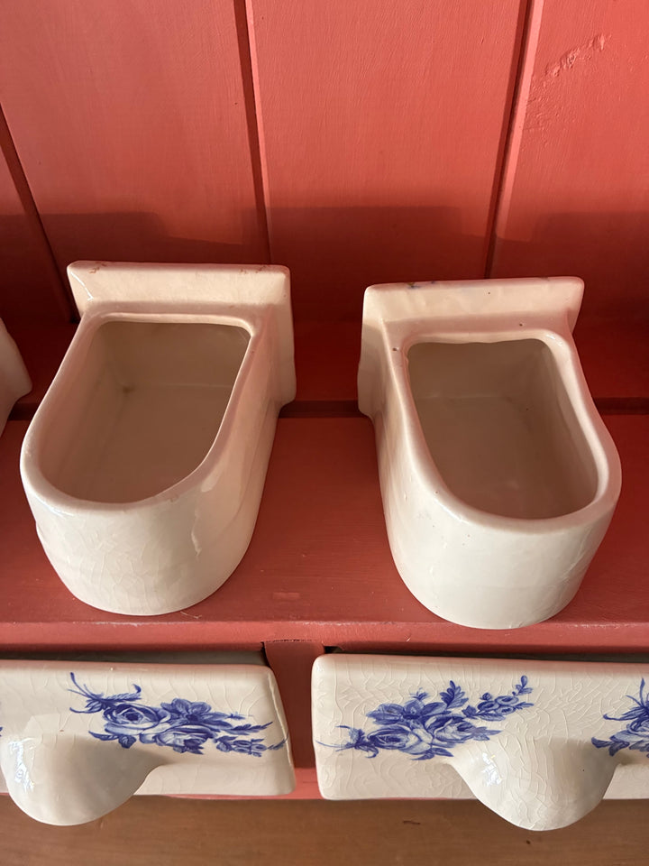 Ceramic spice drawers with a classic design, featuring creamy white and blue floral accents, set against a salmon-toned background.