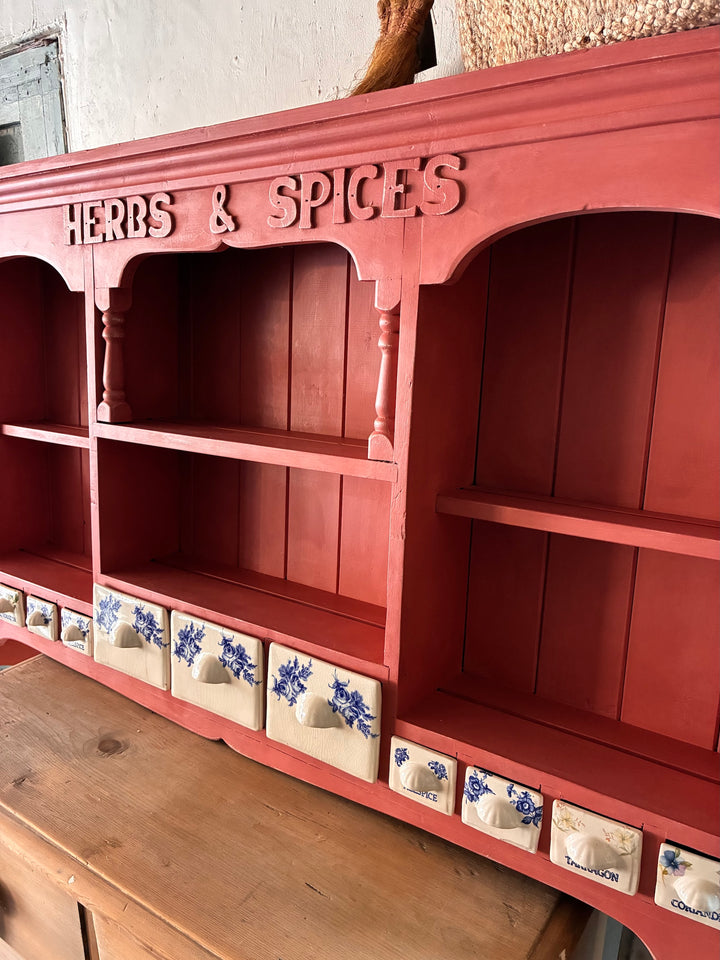 Wall mounted plate rack with herbs and spices drawers in salmon pink, featuring ceramic blue accents.