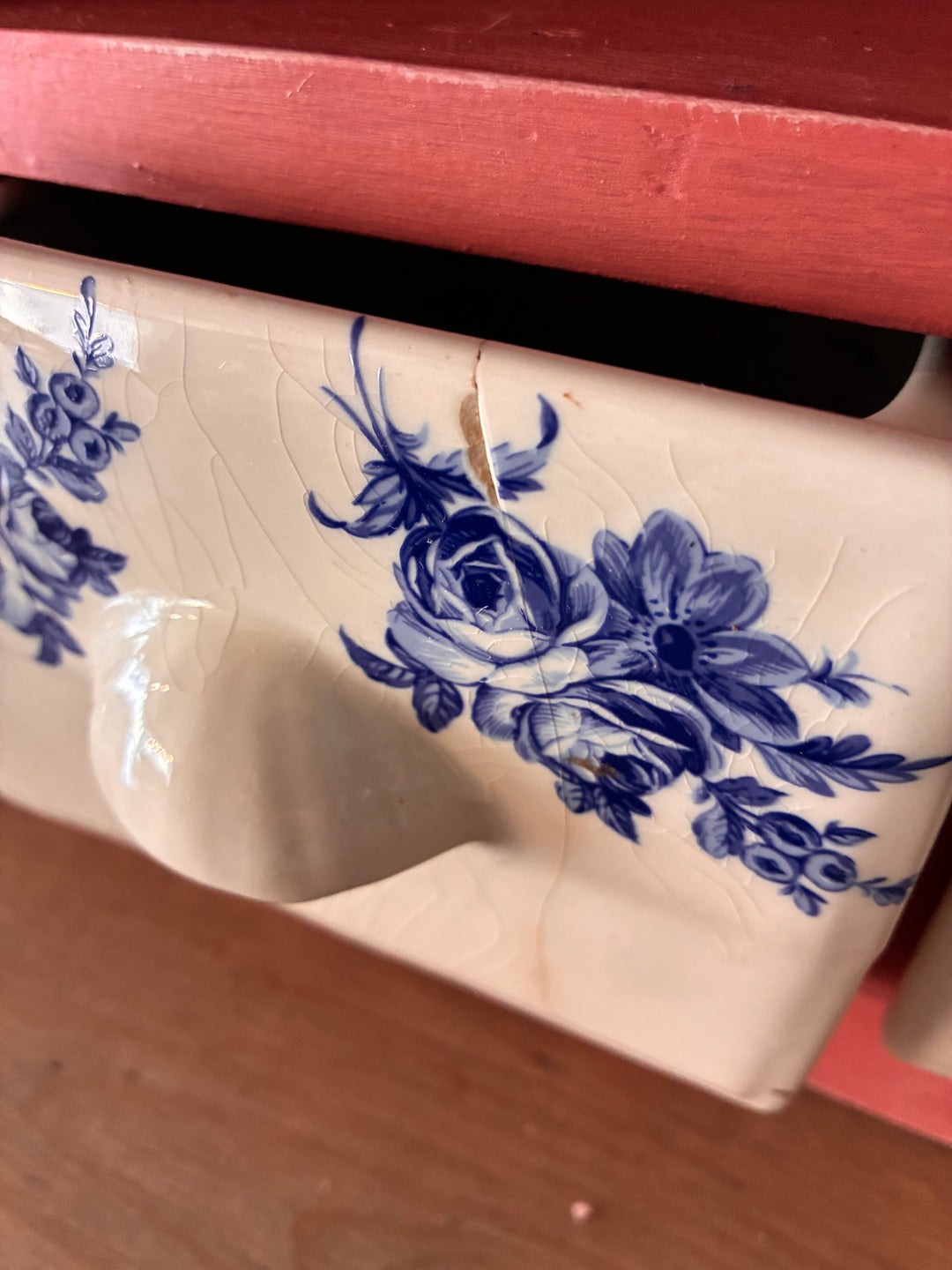 Close-up of a ceramic drawer with blue floral designs, featuring a vintage finish, from the wall-mounted plate rack.