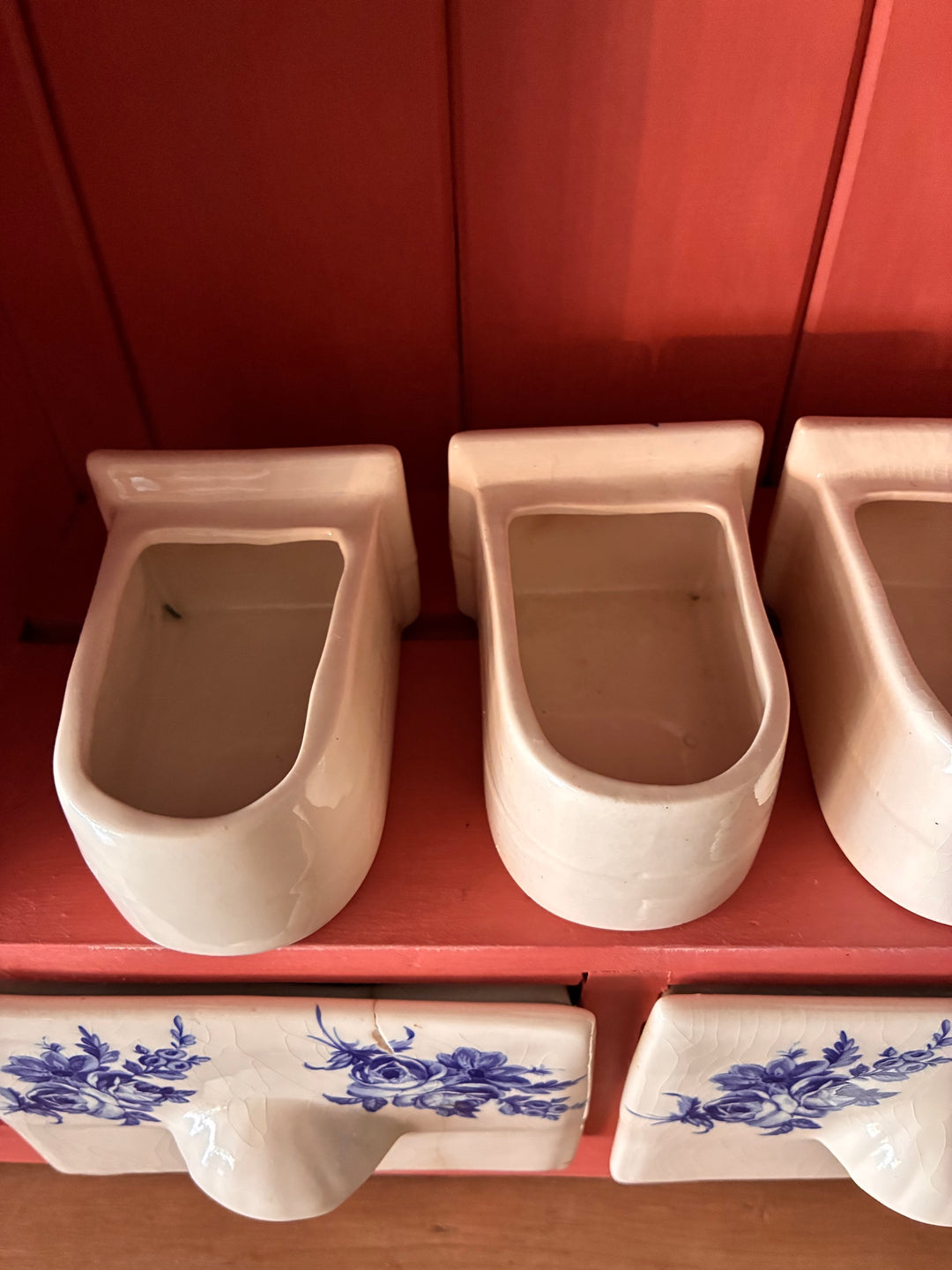 Ceramic spice drawers in salmon-toned pink wall-mounted plate rack by Source for the Goose, Devon.