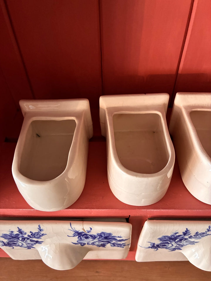 Ceramic spice drawers in salmon-toned pink wall-mounted plate rack by Source for the Goose, Devon.