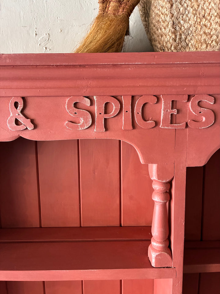 Close-up of a distressed salmon pink cabinet detailing 'herbs & spices' for a rustic kitchen decor by Source for the Goose.