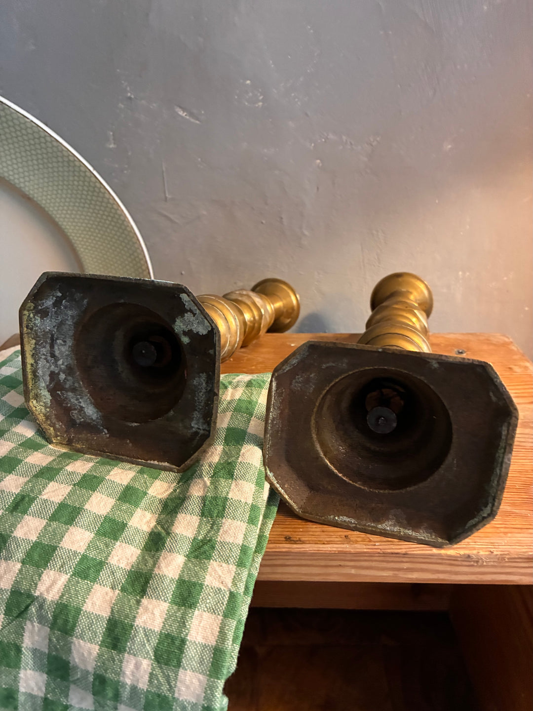 Pair of Antique Brass Candlesticks showing authentic patina on a wooden surface.