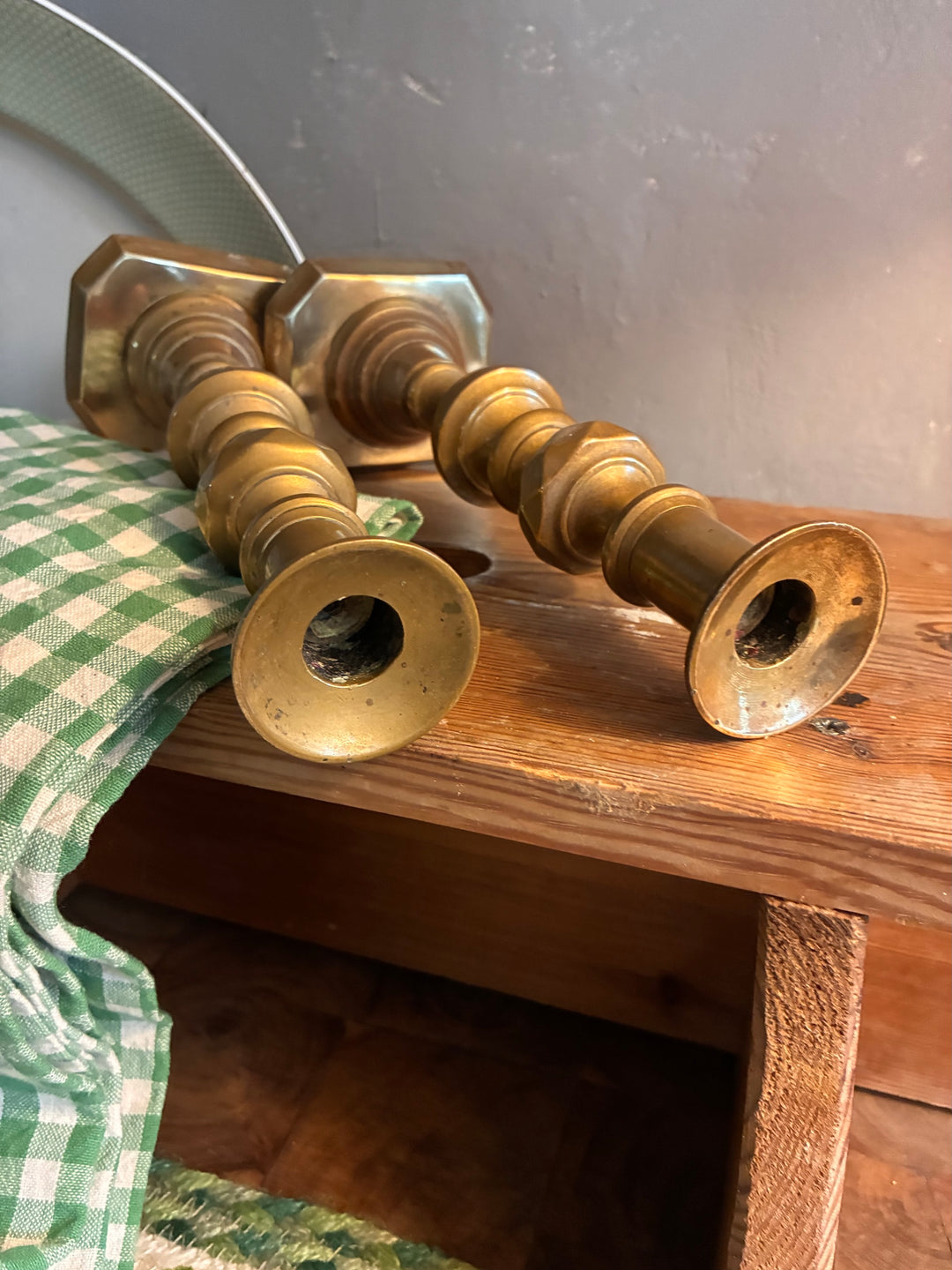 Pair of Antique Brass Candlesticks on a wooden table with a green checkered cloth.