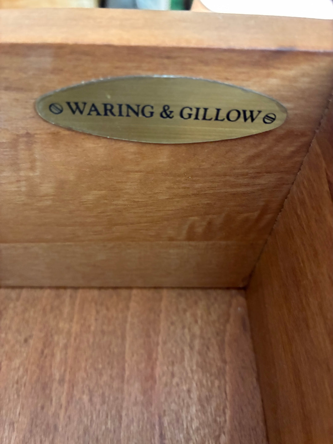 Waring & Gillow brass plaque inside wooden cabinet, highlighting craftsmanship and heritage.