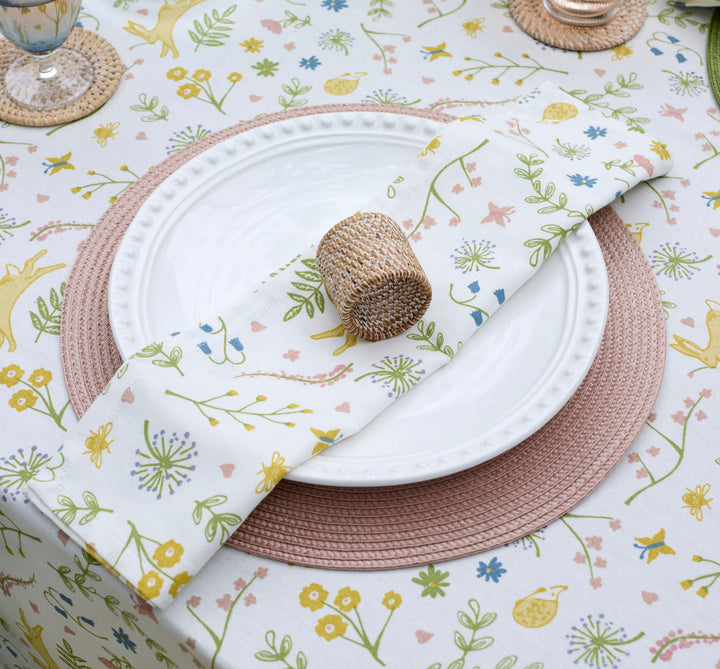 Table setting with floral tablecloth, white plate, woven napkin, and woven pink circular placemat at Source for the Goose, Devon
