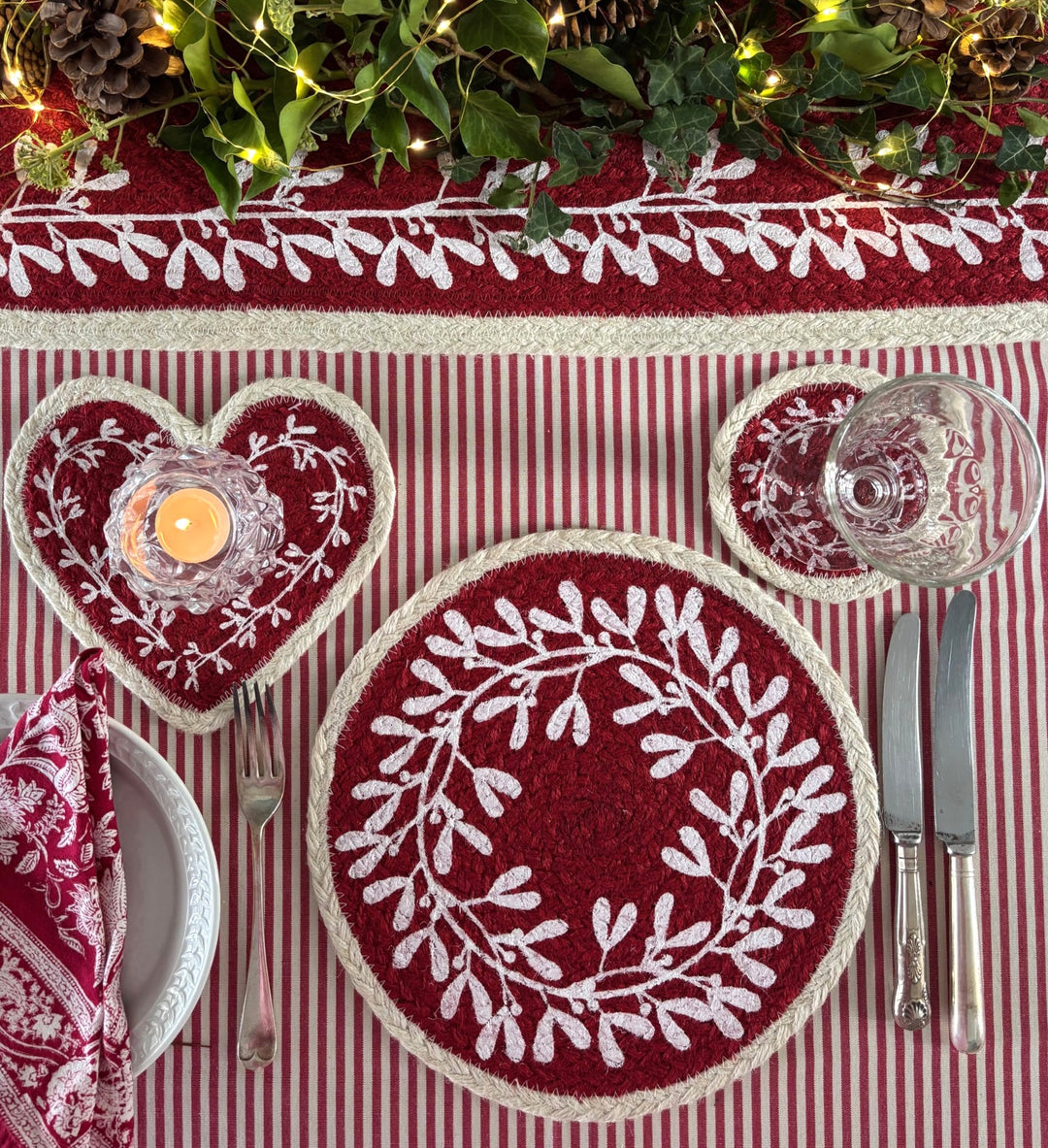 Heart Shaped Red Berry Jute Coaster with white mistletoe design on a festive table setting.
