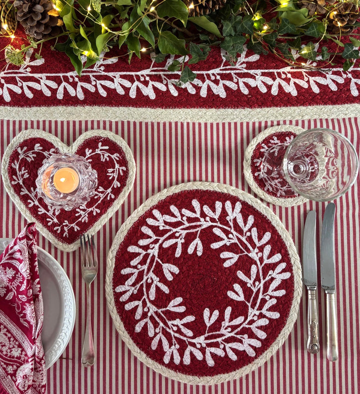 Heart Shaped Red Berry Jute Coaster with white mistletoe design on a festive table setting.