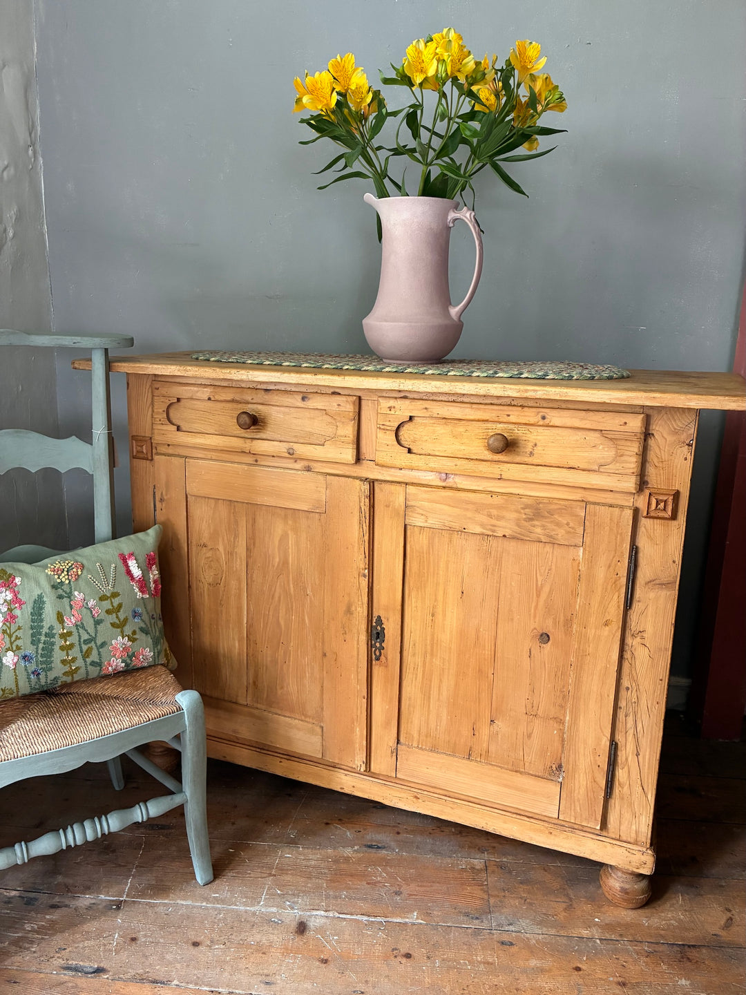 Rustic Antique Pine French Cupboard with a floral arrangement and vintage decor in a cozy setting.