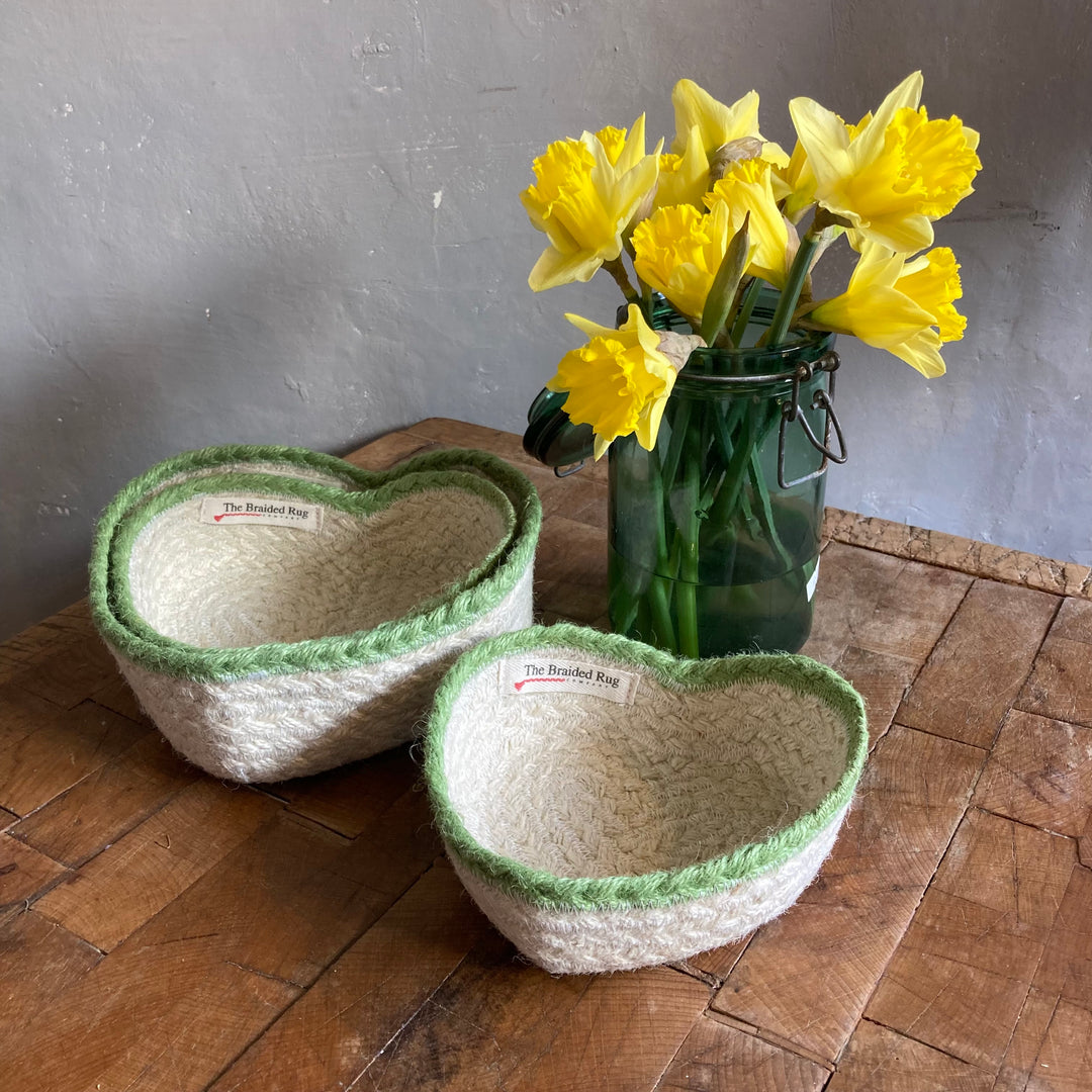 Set of Three Jute Heart Baskets in front of a vintage green jar with daffodils